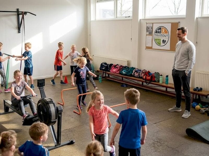 Een sportinstructeur geeft training aan een grote groep kinderen in de gymzaal.