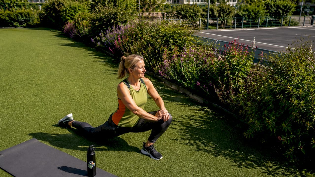 Een vrouw begint haar warming-up in een groen park, omringd door de natuur.