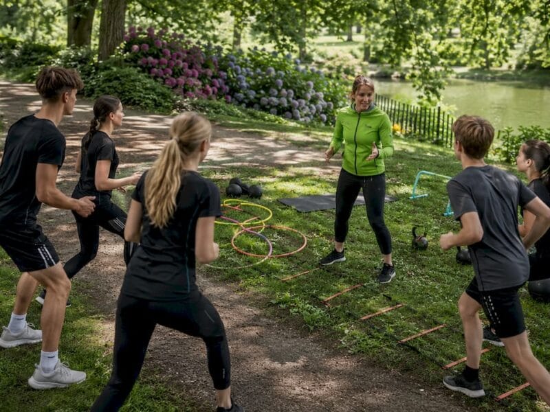Buiten coacht de trainer een groepje jonge sporters.