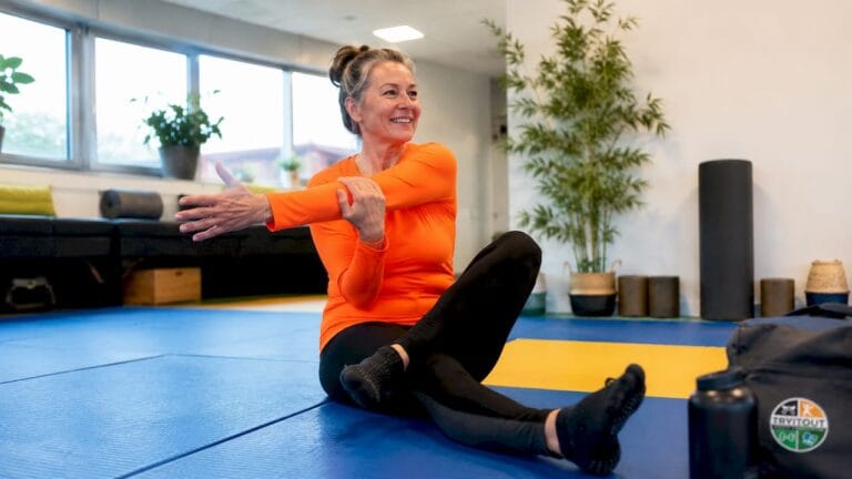 Een vrouw is bezig met stretchoefeningen in de sportschool.