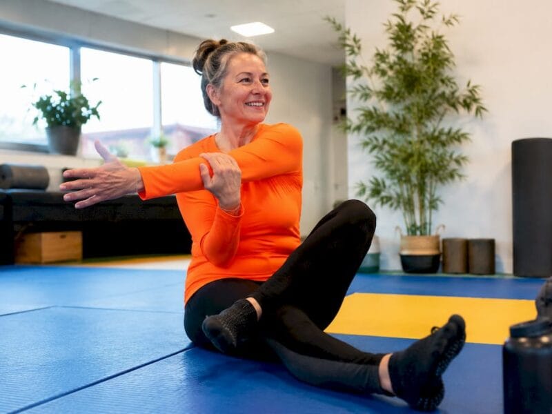 Een vrouw is bezig met stretchoefeningen in de sportschool.