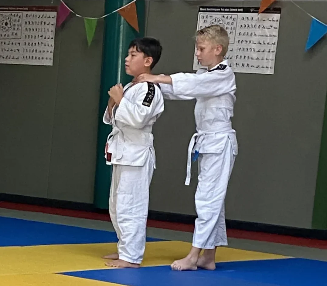 Trainer begeleidt kinderen tijdens een veilige jujutsu jeugdles bij TRYITOUT