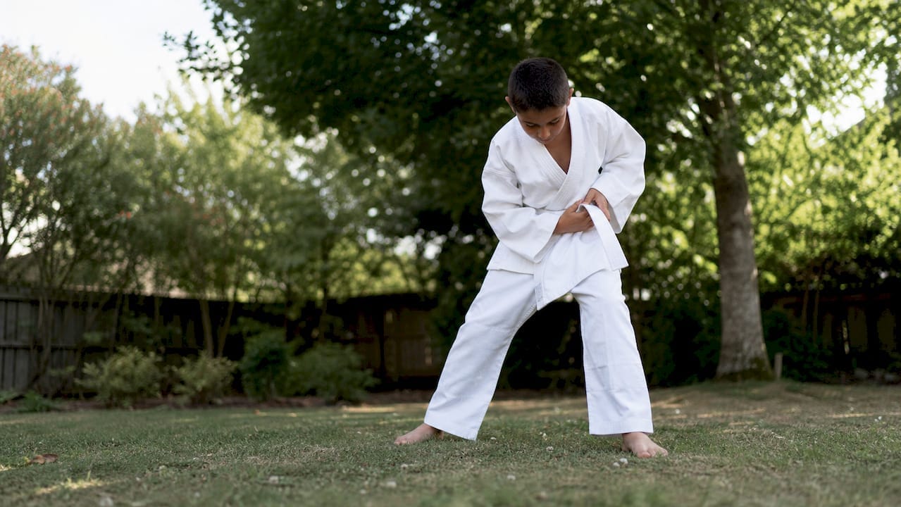 Thuis probeert een kind het judopak uit en beweegt er lekker in rond.