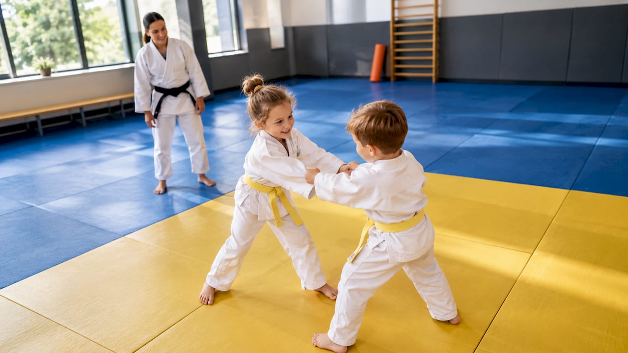 Kinderen oefenen samen tijdens de judoles