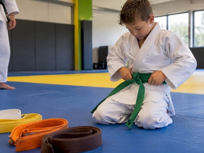 Jonge judoka knoopt zijn groene band vast